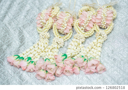 Beautiful Thai-style jasmine garland on a silver cloth background with an ancient Thai pattern. Beautiful Thai-style jasmine garland on a silver cloth background with an ancient Thai pattern. 126802518