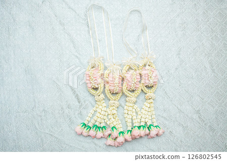 Beautiful Thai-style jasmine garland on a silver cloth background with an ancient Thai pattern. Beautiful Thai-style jasmine garland on a silver cloth background with an ancient Thai pattern. 126802545