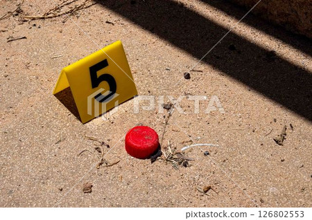 One yellow crime scene marker on the paving slab near the bottle cap. High quality photo 126802553