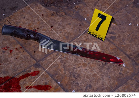 Bloody handprint and bloody knife at crime scene with yellow evidence marker. High quality photo 126802574