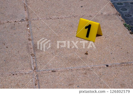 One yellow crime scene marker on the paving slab. High quality photo One yellow crime scene marker on the paving slab. High quality photo 126802579