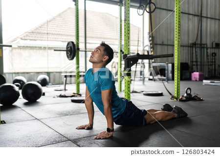 Fitness Stretching Routine. Man performing yoga stretches in a gym. 126803424