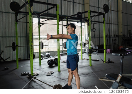 Fitness Focus. Young man stretching arms in gym for workout preparation. 126803475