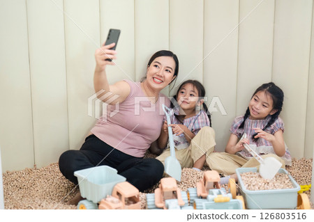 Family Bonding: Mother and Daughters Playing Together in a Playroom Family Bonding: Mother and Daughters Playing Together in a Playroom 126803516