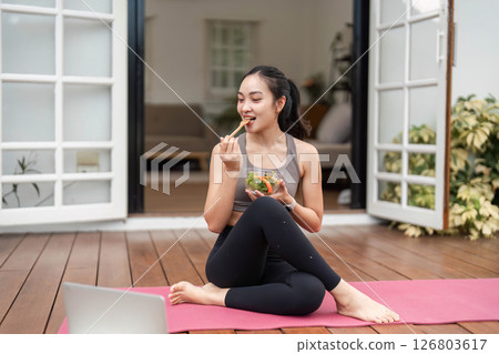 Mindful Eating and Yoga. Woman enjoying a nutritious meal on a yoga mat in a cozy setting. 126803617