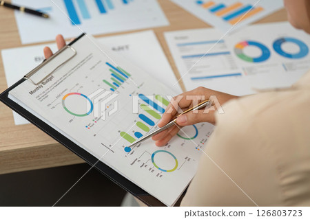 Budget Analysis. Professional reviewing monthly financial reports in a meeting. 126803723