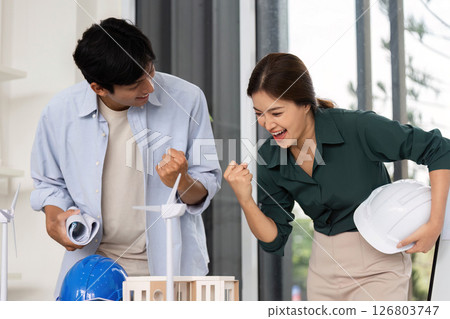 Sustainable Architecture Collaboration. Two architects celebrating project success in modern office. Sustainable Architecture Collaboration. Two architects celebrating project success in modern office. 126803747