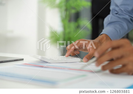 Efficient Data Entry. Professional using calculator while analyzing reports on a desk. Efficient Data Entry. Professional using calculator while analyzing reports on a desk. 126803881