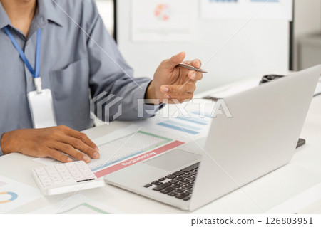 Remote Work and Digital Transformation. Professional analyzing data on laptop with documents. Remote Work and Digital Transformation. Professional analyzing data on laptop with documents. 126803951