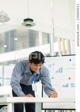 Engaged Professional in Data Review. Young man writing notes while analyzing business charts. 126804011