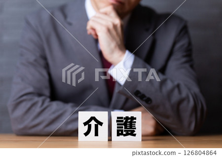 A middle-aged male businessman wearing a suit and worrying about nursing care blocks 126804864