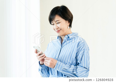 A middle-aged woman who operates a smartphone 126804928