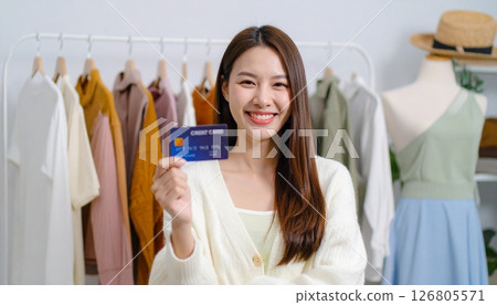 一位女士拿著卡片，在衣服的背景下做出「OK」手勢 126805571