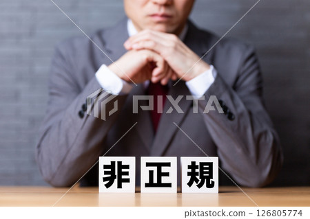 A middle-aged male businessman wearing a suit and worrying about non-regular employee blocks A middle-aged male businessman wearing a suit and worrying about non-regular employee blocks 126805774