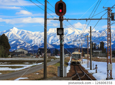 The Toyama Chiho Railway enters Tsukioka Station with the snow-capped Tateyama mountain range in the background. The Toyama Chiho Railway enters Tsukioka Station with the snow-capped Tateyama mountain range in the background. 126806358