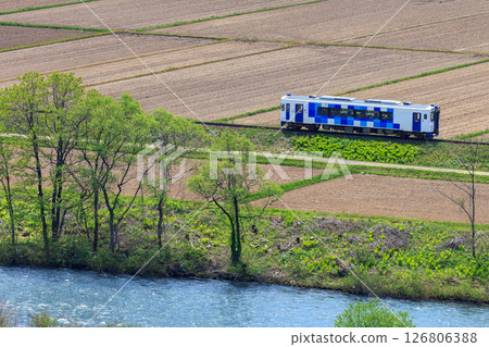 Yuri Kogen Railway diesel railcar running through fields waiting for spring 126806388