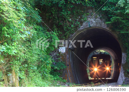 一列山陰本線柴油列車在車頭燈的照耀下穿過一條短隧道。 一列山陰本線柴油列車在車頭燈的照耀下穿過一條短隧道。 126806390