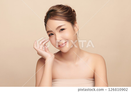 A beautiful young Asian woman with clean, fresh skin against a beige background. Skincare, facial treatment, cosmetology, beauty, and spa. An elegant portrait of an Asian woman. 126810902