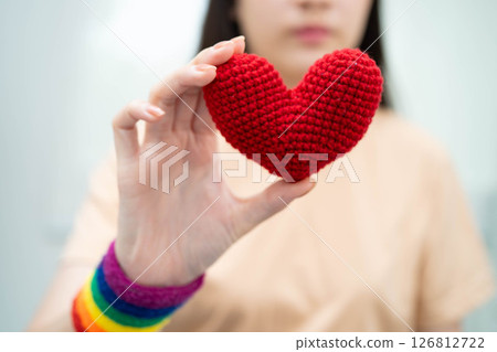 Asian woman holding LGBT heart with rainbow flag. Asian woman holding LGBT heart with rainbow flag. 126812722