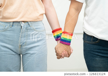 Asian LGBT couple woman holding hand wearing rainbow wristband. 126813124