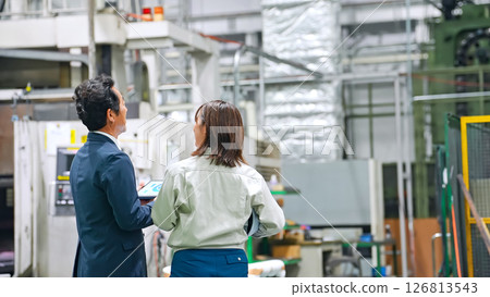 A male business person and a female worker inspecting a factory 126813543