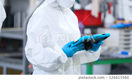 Worker in protective clothing using tablet PC in factory Worker in protective clothing using tablet PC in factory 126813560