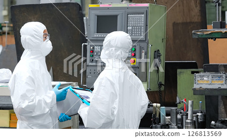 Male and female workers in protective clothing operating machines in a factory 126813569
