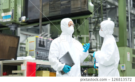 穿著防護衣的男女工人在工廠交談 穿著防護衣的男女工人在工廠交談 126813572