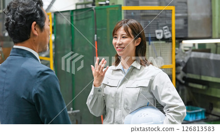 A male business person and a female worker having a conversation in a factory A male business person and a female worker having a conversation in a factory 126813583