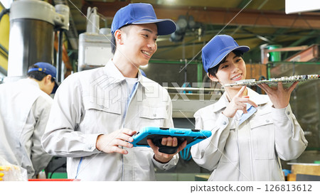 Male and female workers inspecting products using a tablet in a factory Male and female workers inspecting products using a tablet in a factory 126813612