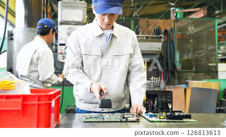 A male worker inspects products using a handheld terminal at a factory A male worker inspects products using a handheld terminal at a factory 126813613