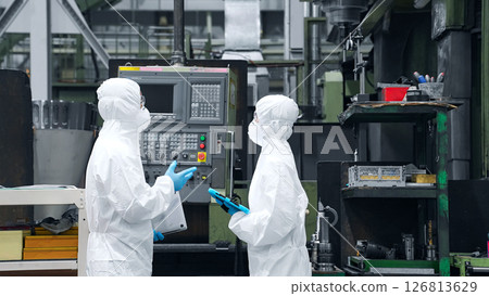 穿著防護衣的男女工人在工廠交談 穿著防護衣的男女工人在工廠交談 126813629