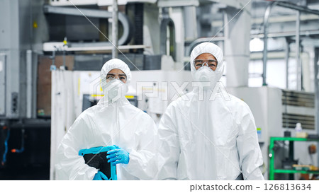 穿著防護衣站在工廠裡的男女工人 126813634