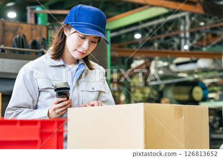 A group of female workers using handheld terminals to manage products in a factory 126813652