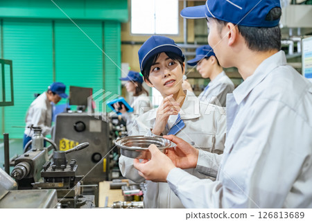 A group of workers operating machine tools in a factory 126813689