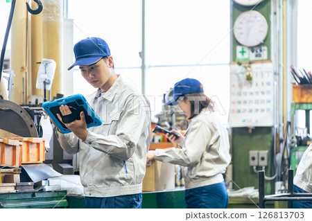 Group of workers holding a tablet working in a factory Group of workers holding a tablet working in a factory 126813703
