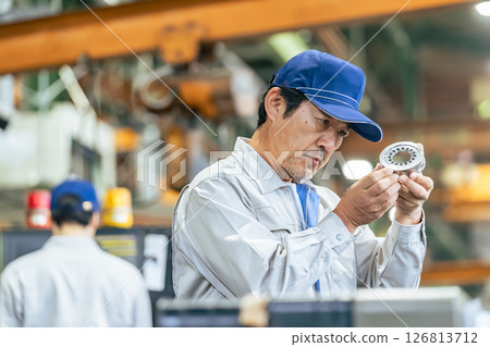 Male worker inspecting products at a factory 126813712