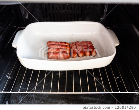 portion of sausages wrapped in bacon in gas oven 126814280