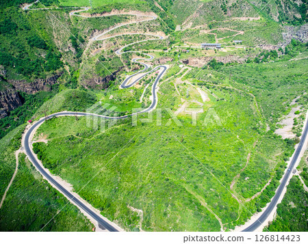 aerial view of green plateau with serpentine road 126814423