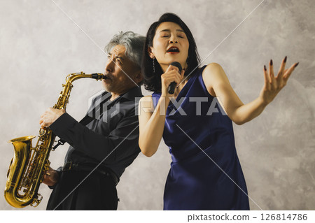 A man playing saxophone and a woman singing 126814786