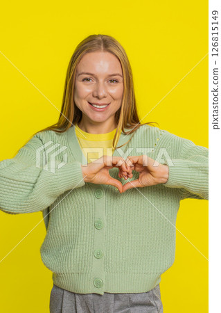 Smiling young woman makes heart gesture demonstrates love sign expresses good feelings and sympathy Smiling young woman makes heart gesture demonstrates love sign expresses good feelings and sympathy 126815149