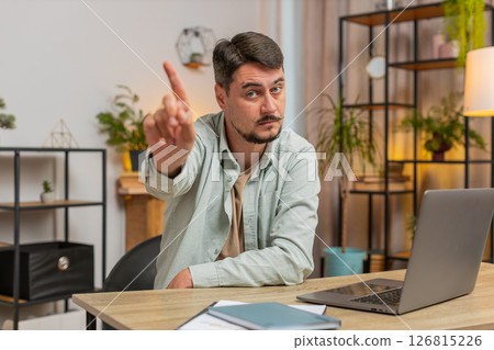 Displeased Caucasian young man freelancer shake finger No sitting at home office desk in living room Displeased Caucasian young man freelancer shake finger No sitting at home office desk in living room 126815226