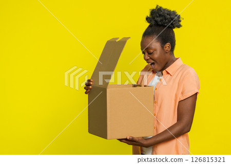 Black woman unboxing delivery package, excited expression, online shopping gift, quick service 126815321