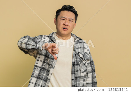 Upset Asian man guy showing thumbs down gesture disapproval dissatisfied dislike negative feedback Upset Asian man guy showing thumbs down gesture disapproval dissatisfied dislike negative feedback 126815341