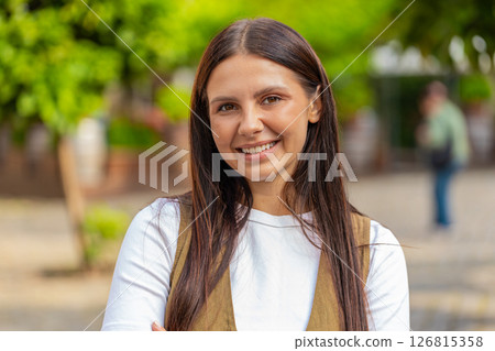 Portrait of smiling brunette young woman friendly glad expression looking at camera on city street Portrait of smiling brunette young woman friendly glad expression looking at camera on city street 126815358