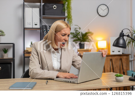 Displeased sad businesswoman using laptop becoming surprised lottery results bad news computer virus 126815396