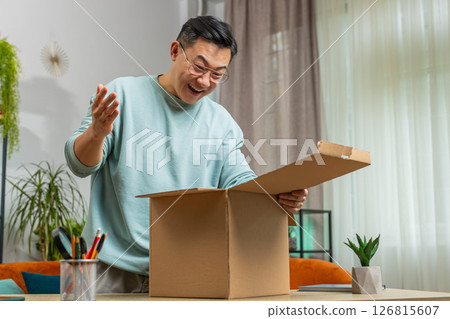 Happy Chinese man shopper unpacking cardboard box delivery parcel online shopping purchase at home 126815607