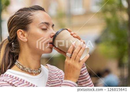 Happy smiling woman walking on city street enjoying morning coffee hot drink relaxing taking a break 126815641