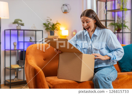 Happy woman girl shopper unpacking cardboard box delivery parcel online shopping purchase at home 126815733