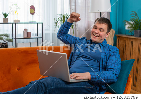 Surprised amazed shocked man using laptop receive good news victory celebrate lottery jackpot win Surprised amazed shocked man using laptop receive good news victory celebrate lottery jackpot win 126815769